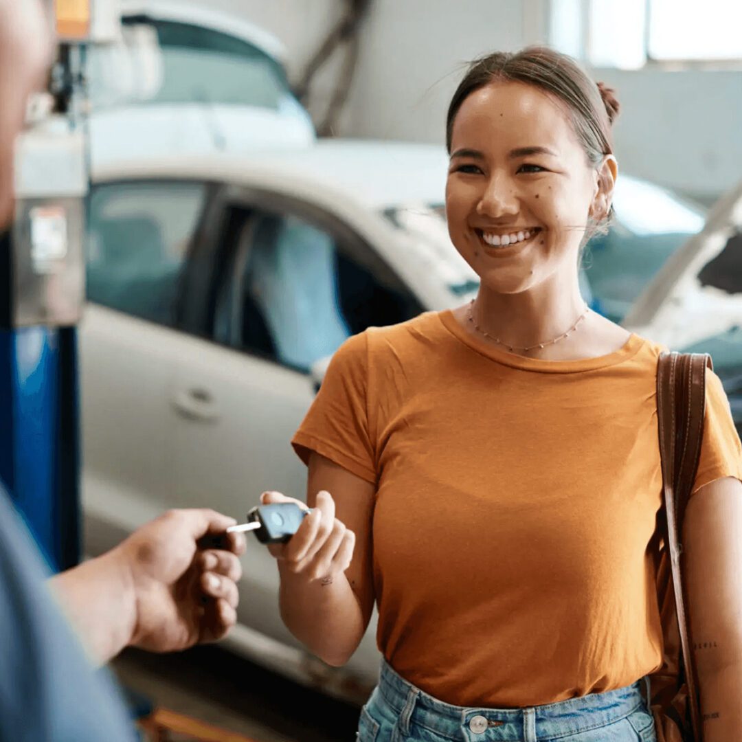 Woman happily receiving car keys from mechanic.
