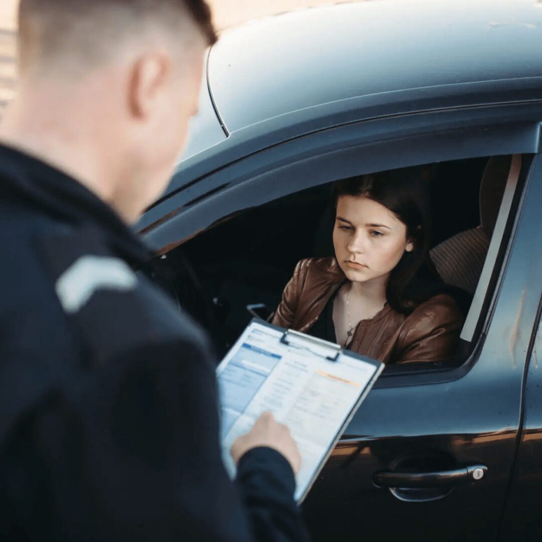 Police officer checking a woman's documents during a traffic stop.