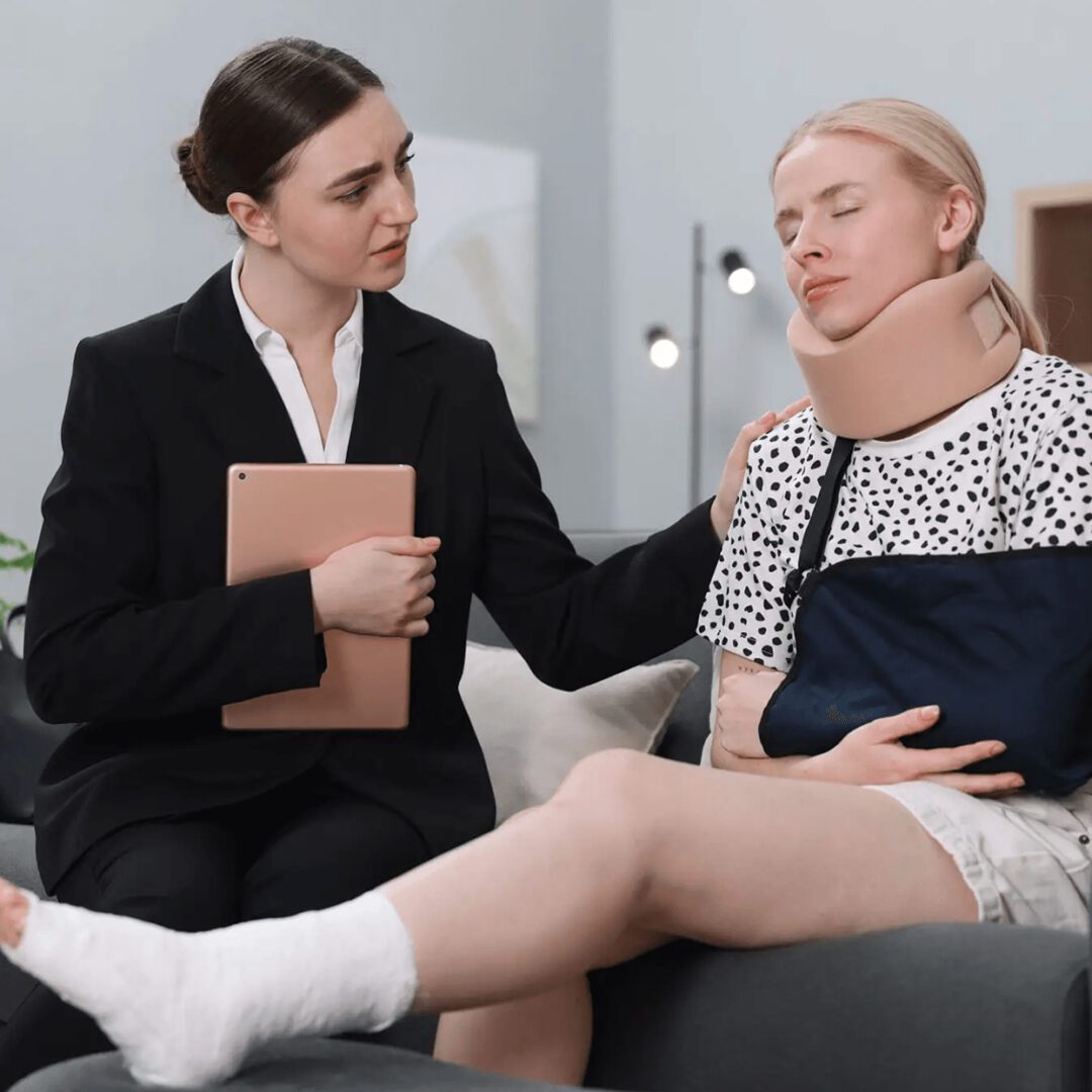 Woman in neck brace being comforted by another woman.