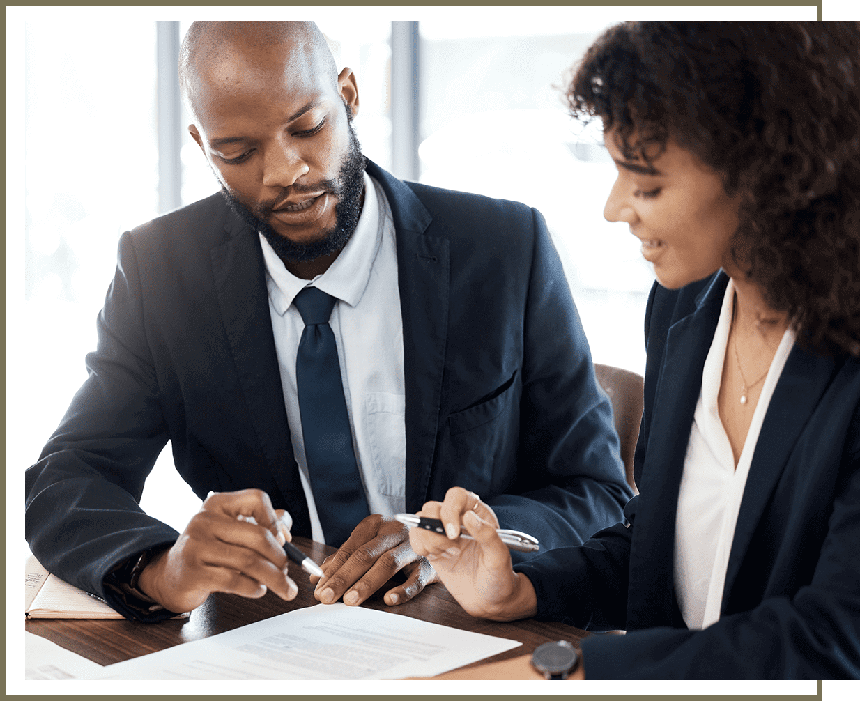 Two professionals discussing documents in a bright office.